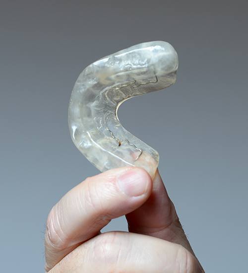 Hand holding a clear occlusal splint to treat T M J dysfunction