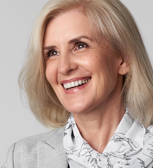 Woman with greying hair smiling while looking up