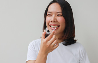 Woman in white shirt putting in a clear aligner