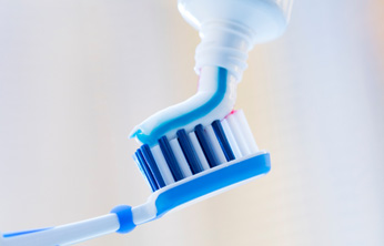 Squeezing toothpaste onto toothbrush
