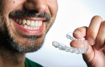 Man with beard holding a clear aligner