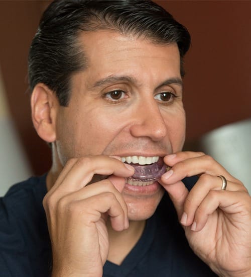 Man placing sleep apnea oral appliance