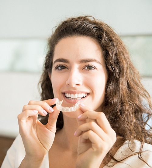 Brown-haired woman putting in clear aligners in San Ramon, CA