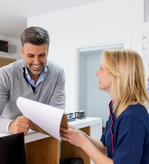 Dental team member assisting patient at front desk