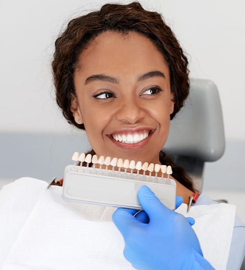 Woman's smile compared to porcelain veneer colors during cosmetic dentistry consultation