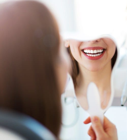 Woman looking at smile after metal free dental restoration