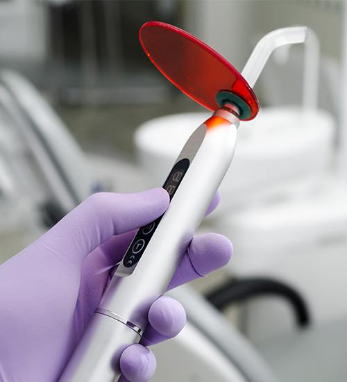 Dentist holding a cosmetic dental bonding curing device