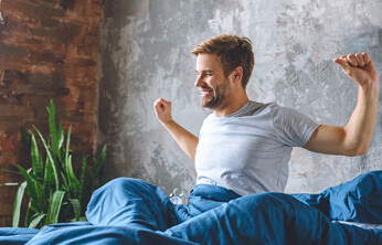 man waking up and stretching in bed