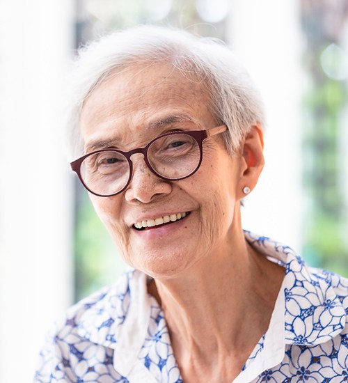 Senior woman with glasses standing and smiling