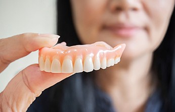 Close-up of woman holding dentures in San Ramon, CA