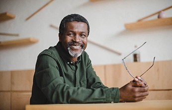 Senior man smiling and holding his glasses