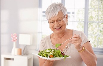 Senior woman smiling and eating a salad