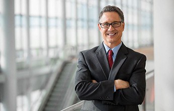 Senior man in suit smiling next to an escalator