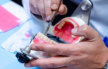 Close-up of technician’s hands carefully working on dentures