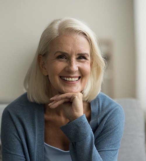 Senior woman smiling and sitting in chair at home