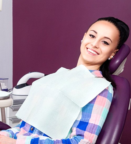 Female patient sitting in dental chair and smiling