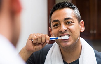 Man brushing his teeth while looking in the mirror