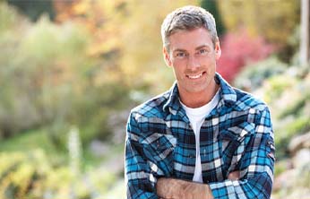 Man smiling outside wearing a blue flannel