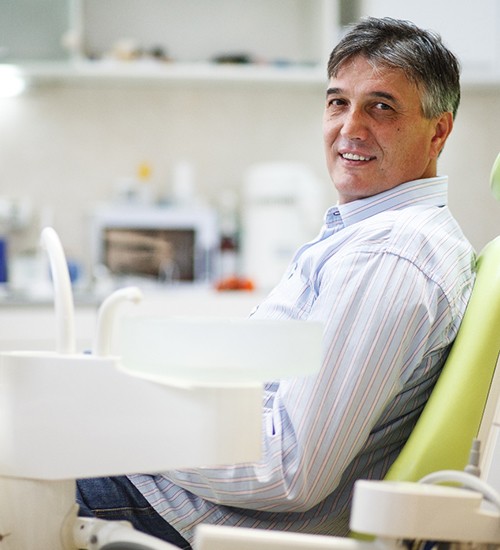 Senior man sitting in dental chair smiling
