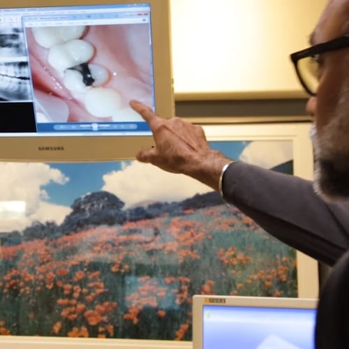 Dentist pointing to clear image of patient's teeth on computer screen
