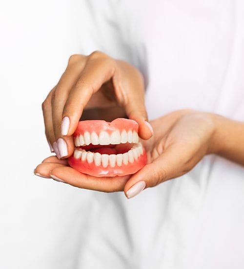 Hand holding full dentures