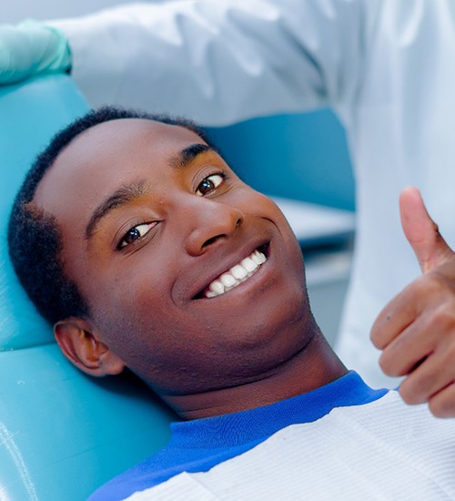 Man smiling giving thumbs up in dental chair