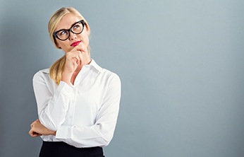 Woman with hand on chin thinking with gray background