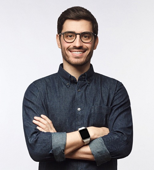 Man smiling with his arms crossed while wearing glasses