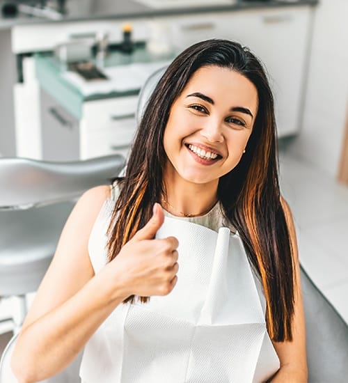 Smiling woman giving thumbs up during preventive dentistry visit