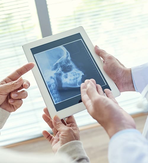 Dentists reviewing paperwork and x-rays during T M J diagnosis and treatment planning