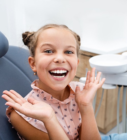 Little girl in dental chair showing off her smile
