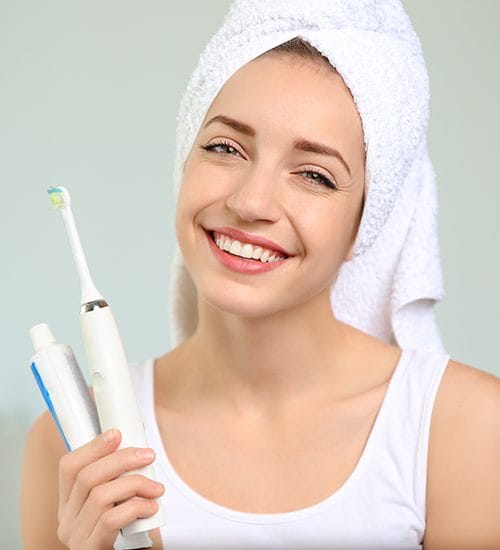 Woman brushing teeth to maintain the results of teeth whitening