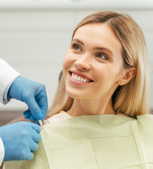 Young woman in dental chair smiling at dentist