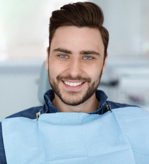 Male dental patient with denim jacket sitting and smiling 