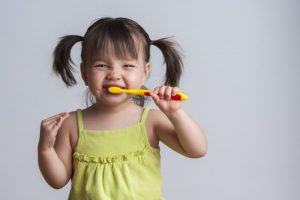 Little girl smiling while brushing her teeth