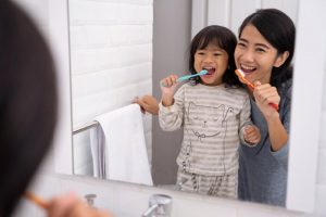 Mother and daughter brushing teeth