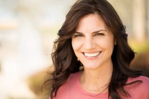 Woman smiling outside after seeing cosmetic dentist