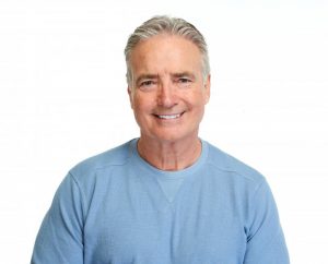 Smiling middle-aged man wearing a blue sweater with white background