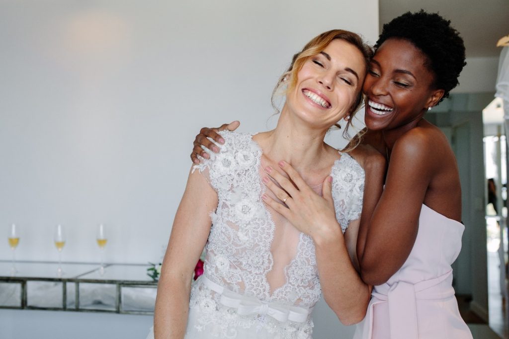 Bride smiling with bridesmaid on wedding day