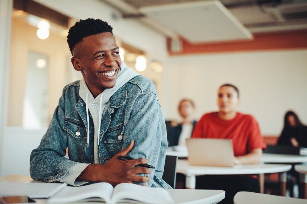 College student in jean jacket smiling in classroom