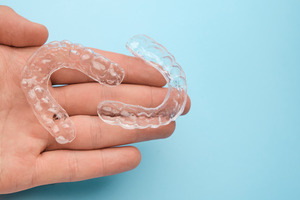 Hand holding a pair of clear aligners