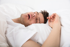 Man with sleep apnea lying in bed and snoring