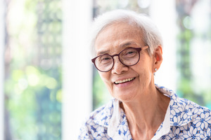 Senior woman with glasses standing and smiling outside 