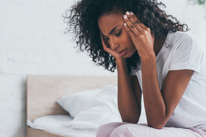 Woman sitting on bed with a headache