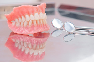 Dentures sitting next to a dental mirror